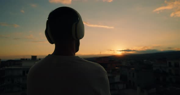 Boy listening to music outdoors while watching the sunset.