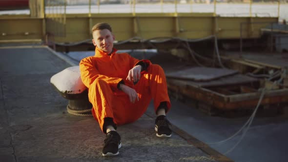 Portrait of Young Worker in Orange Uniform Sitting During His Break By the Sea