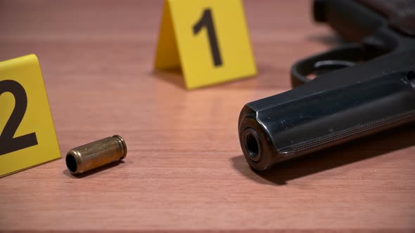 on the Crime Scene, on the Floor, Lay a Pistol and Shell Casing Marked with Photo Markers