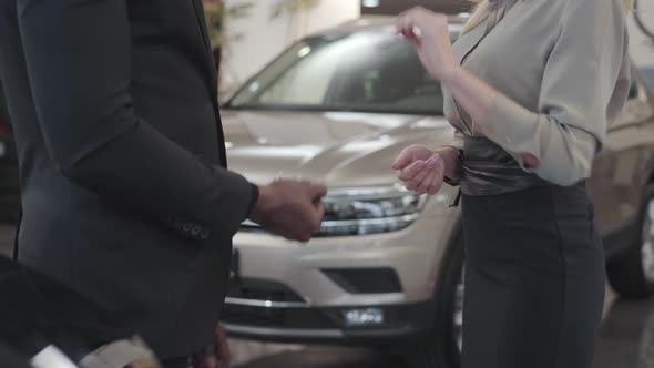 Close-up of Two People Shaking Hands at the Background of New Automobiles