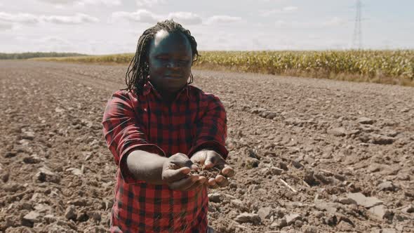 African Farmer Holding Soil in His Hands. Medium Shot on the Farm