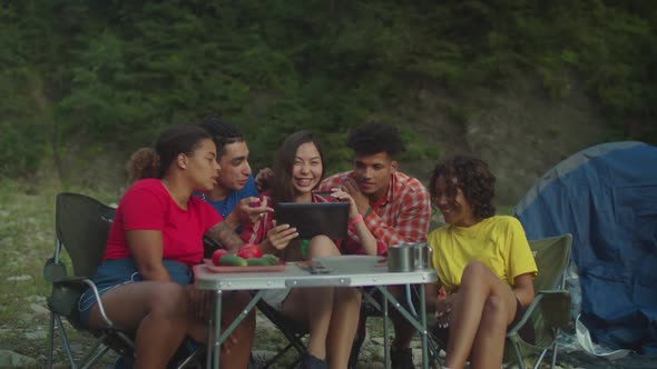 Group of Joyful Diverse Multiethnic Hikers Sharing and Browsing Online on Tablet Pc in Camping Trip