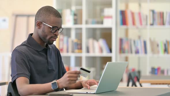 African Man Having Online Payment Failure on Laptop in Library