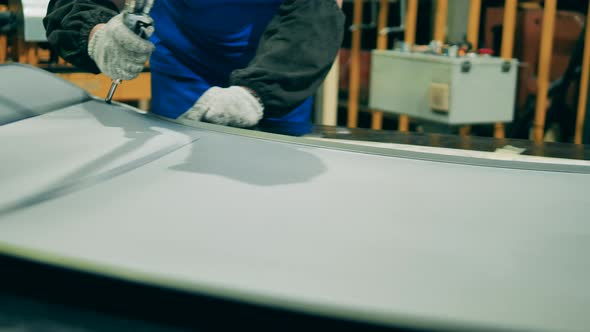 Car Manufacturing Worker Cutting Out Car Body Part at a Car Factory