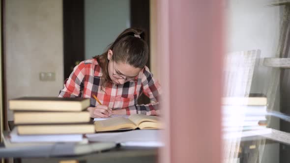 camera moves outside the window, showing girl who is preparing for exams