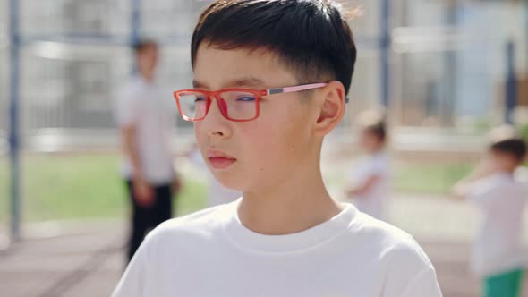 Portrait of Primary School Asian Child Standing and Turn Head Looking at Camera on Basketball Court