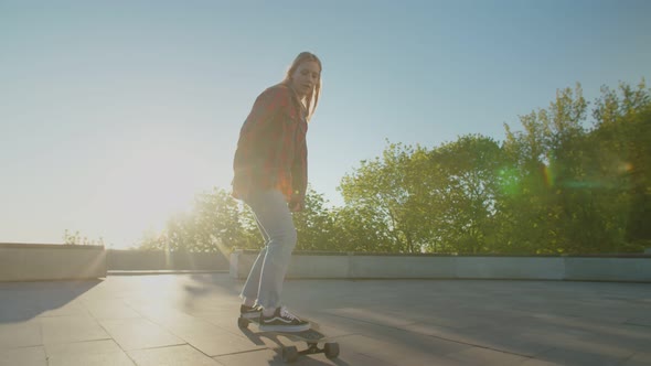 Beautiful Young Female Skater Riding on Longboard at Daybreak