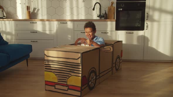 Joyful School Age African American Boy Playing with Crafted Toy Cardboard Car