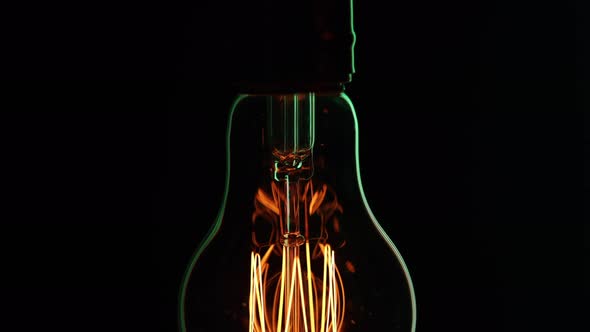 Close up silhouette of a glowing light bulb in the dark.