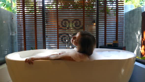 Young Woman Relaxing in Bathtub with Foam