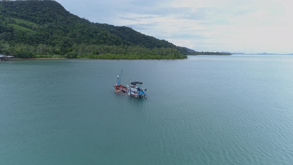 Stunning aerial shot of a sinking fishing boat off the coast of a mountainous island in Thailand