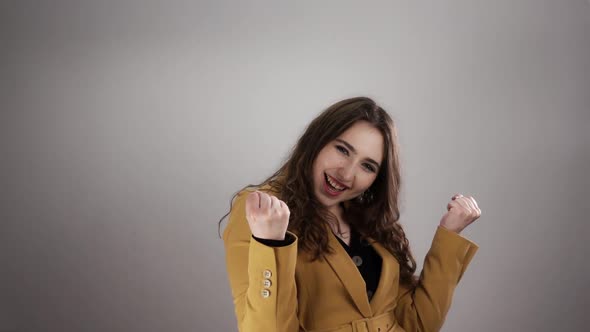 Portrait of Happy and Satisfied Woman Who Clenches Her Fists in a Slow Motion on White Background