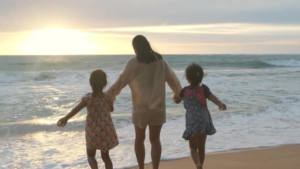 Happy Asian family of mother and daughters having fun playing on the beach during summer.