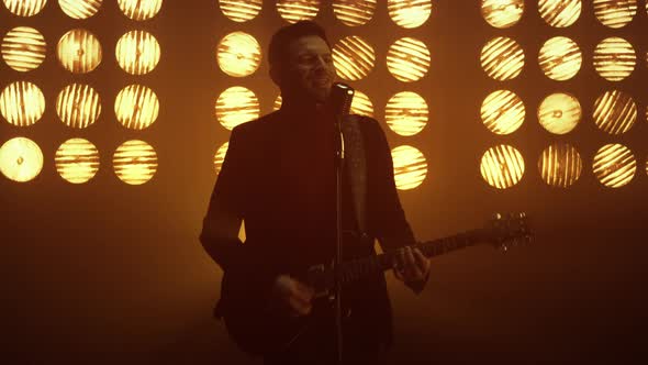 Man Singing Microphone Playing Guitar on Stage