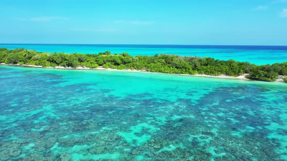 Wide fly over abstract shot of a white sandy paradise beach and blue water background in vibrant 