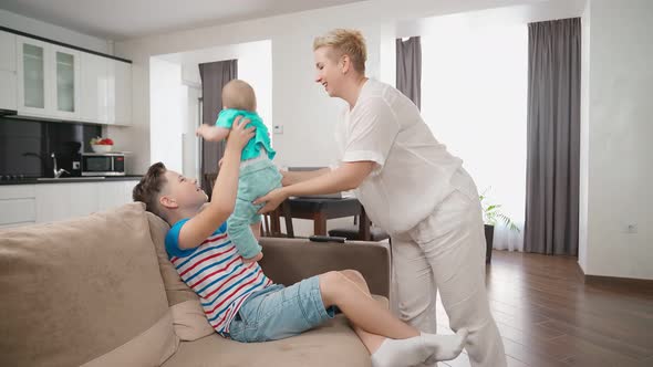 Woman Working on Laptop While Two Sons Relaxing on Sofa