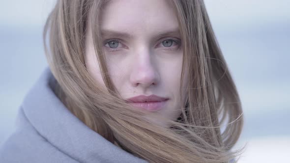 Beautiful Young Blond Woman with Long Hair and Blue Eyes Looking in the Camera