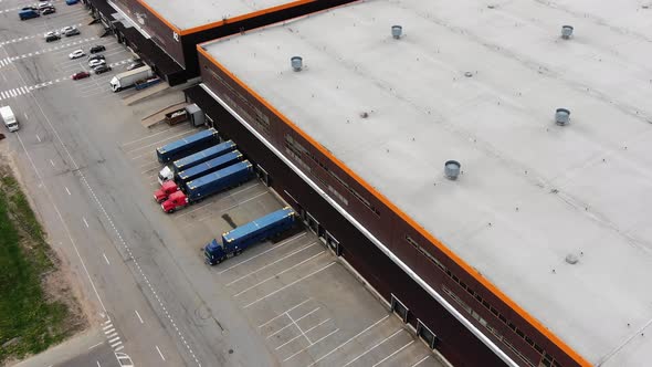 Large Warehouse with Trucks and Cars on Parking Lot