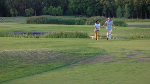 Carefree Senior Couple Having Fun While Running Nature