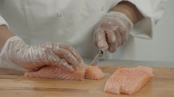 Close up of Professional male chef hand using fish fillet knife slice fresh orange salmon meat on cu