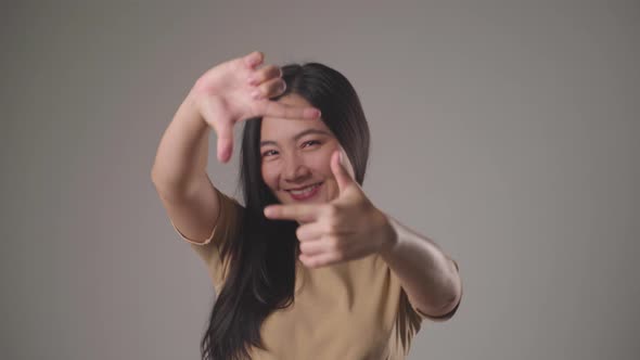 Confident asian woman happy making finger frame smilling and looking at camera