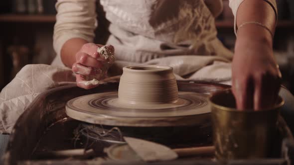 Young Woman Potter Wetting Her Hands and Forming the Clay with Her Fingers