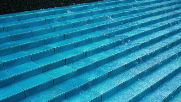 Water Flows Down the Blue Ceramic Steps in Fountain in City Park.