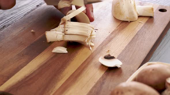 Men Hands Cutting Champignons with a Knife on Kitchen Table