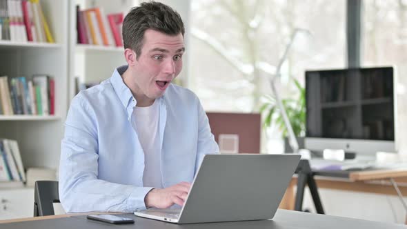 Excited Young Man Celebrating Success on Laptop