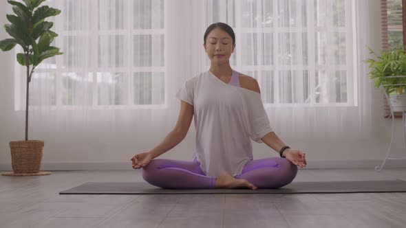 After waking up at home, a woman does morning yoga