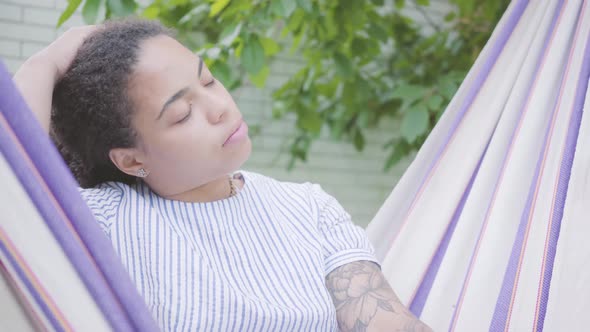 Close-up Portrait of Young Smiling African American Woman Sitting in the Hammock