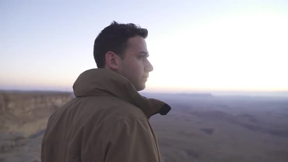 Man looks at the rising sun in a desert scenery