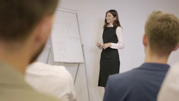 Cute Businesswoman Presenting New Project To Partners with Flip Chart