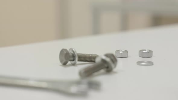 Screwnuts Bolts Wrench Lie on a White Surface