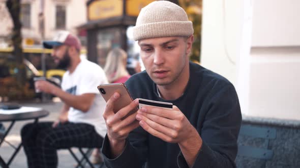 Portrait Man Buying Online Uses a Phone and a Credit Card in Outdoor Cafe Smile Shopping Cellphone 