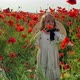 Happy girl in a field of blooming red poppies. Leisure in nature. Enjoying - VideoHive Item for Sale