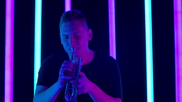 Portrait of a Caucasian Musician Playing the Trumpet in the Studio Against the Backdrop of Bright