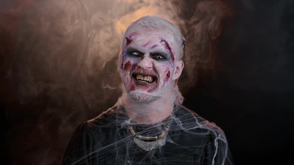 Zombie Man with Wounds Scars and Contact Lenses Looking at Camera Clicks His Teeth Trying to Scare