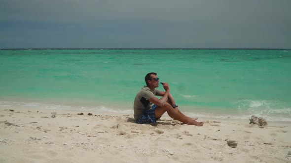 A Man Sits on a Tropical Beach