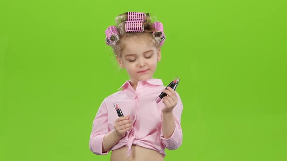 Little Girl in Curlers Chooses the Most Beautiful Lipstick. Green Screen
