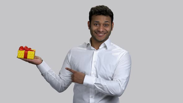 Happy Hindu Man Holding Gift Box and Pointing with Finger