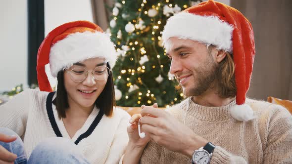 Mixed Race Male and Female Listening to Music Through Earphones Connected to Cellphone Sitting on