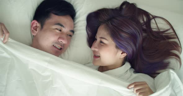 Happy Asian husband and pregnant wife spend time together in the bedroom in the morning.