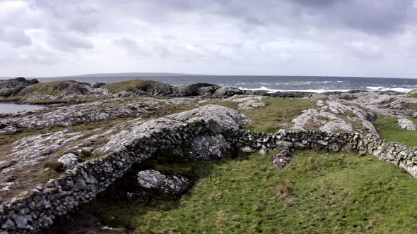 Aerial View of Irish Coast Green Fields Rocks Rough Sea in the Background in a Cloudy Day