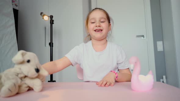 Smiling young caucasian girl blogger vlogger sit at home speaking looking at camera talking