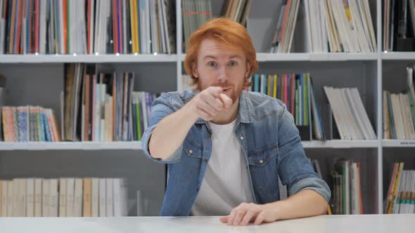 Man with Red Hairs Pointing Toward Camera in Library