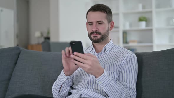 Attractive Young Man Using Smartphone at Home