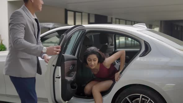 Young Asian Woman in Pink Dress Getting Out of Car, the Driver Holding the Door Open Politely, Lady