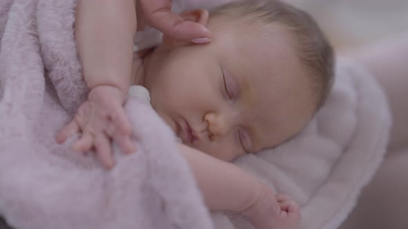 Closeup Sleeping Infant with Female Finger Caressing Cheek