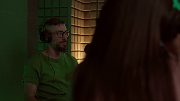 Young man talking in mic while recording podcast with crop coworker